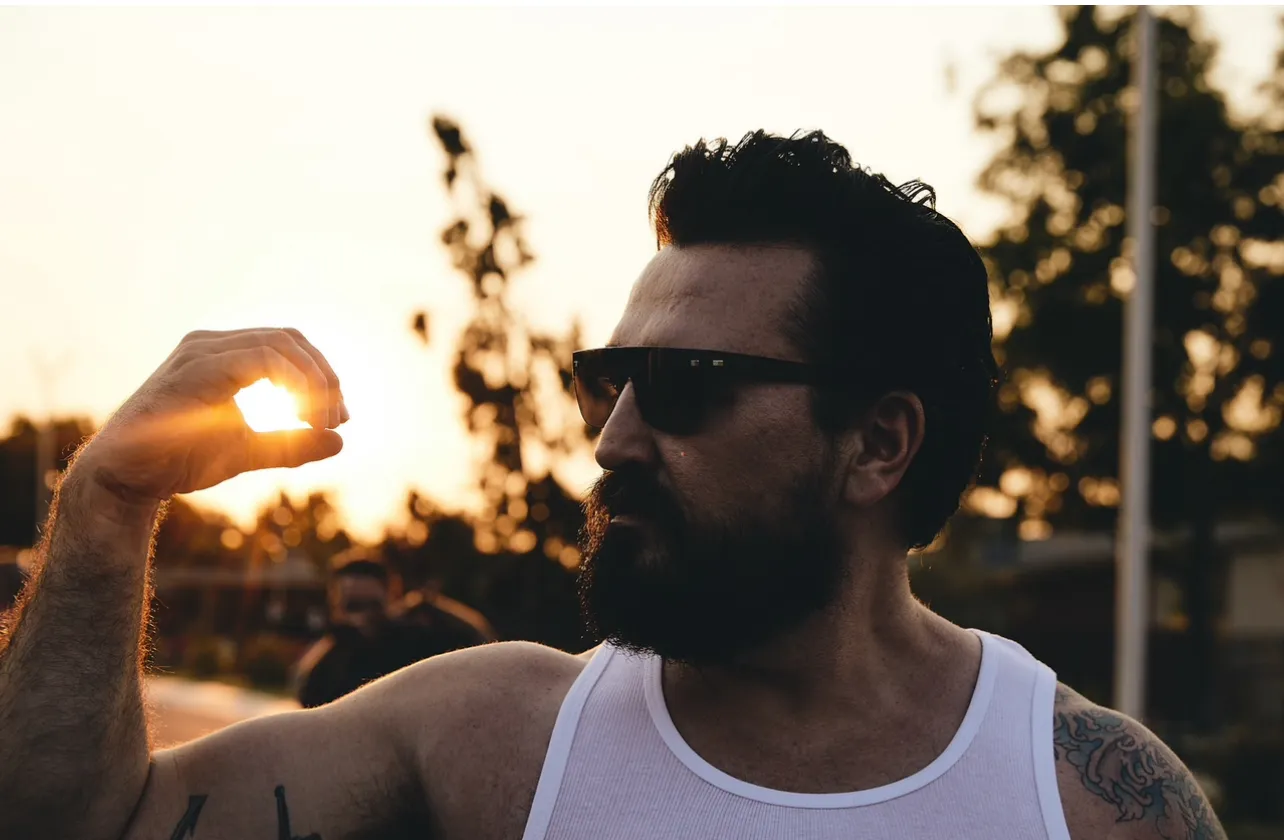 Chris Selgado back lit holding up his hand to frame the sun.